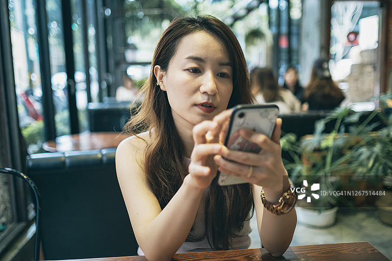 年轻女子坐在咖啡馆里使用智能手机图片素材