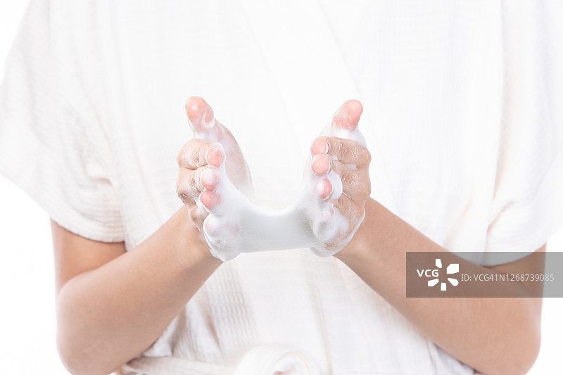 特写手妇女洗她的脸与泡沫洗面奶在早上孤立的白色背景。图片素材