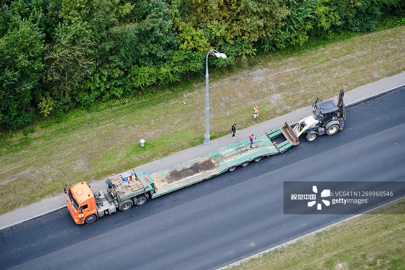 2020年8月24日，俄罗斯，莫斯科，将拖拉机装载到运输农业机械的卡车平台上图片素材