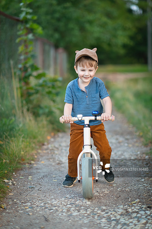 可爱的小男孩在夏天的公园里骑自行车图片素材