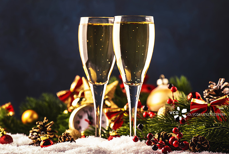 两个香槟杯和圣诞装饰在蓝雪金色的散景背景。庆祝新年快乐。选择性聚焦和小景深图片素材