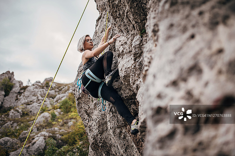 年轻女子在大自然中攀登岩石图片素材