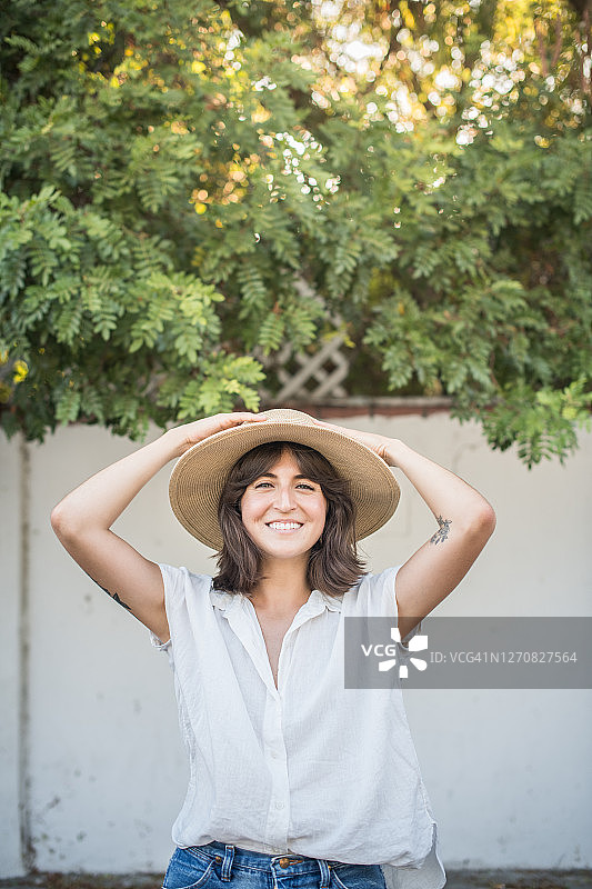 年轻的墨西哥妇女戴着草帽在后院微笑图片素材