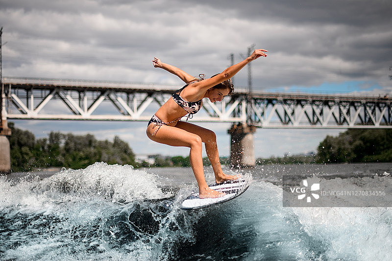 活跃的女人在冲浪板上积极地骑着波浪图片素材