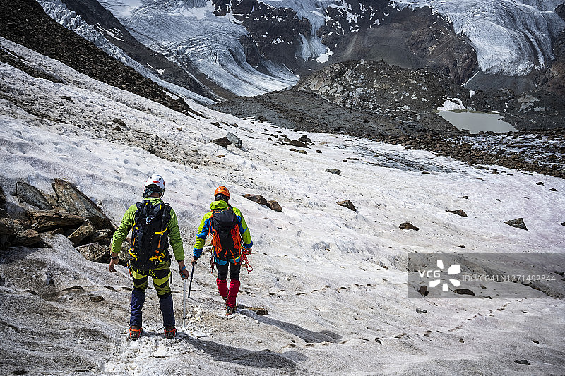 登山运动员在山上冰川的冰碛上徒步旅行图片素材
