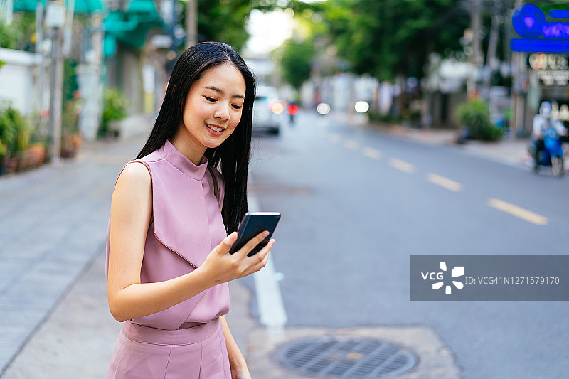 快乐的亚洲女商人在街上用电话图片素材