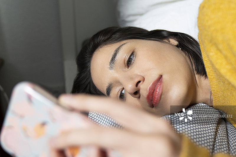 躺在床上玩手机的女性图片素材