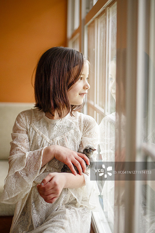 橱窗里映出一个快乐的小女孩，手里拿着一只小鸡图片素材