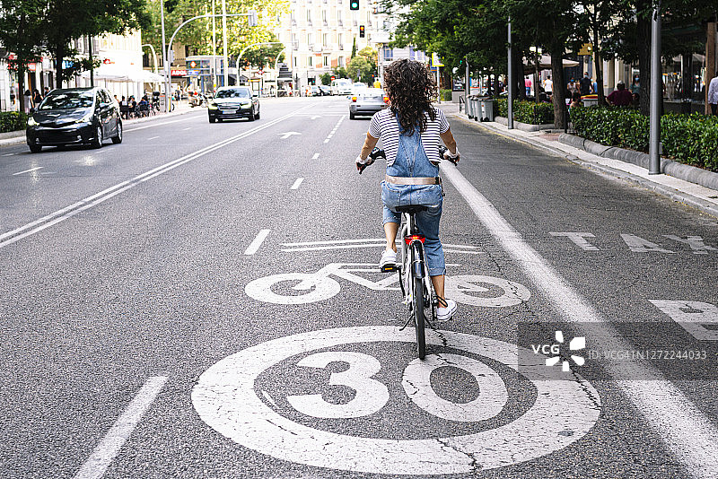 成熟的女人在城市的自行车道上骑车图片素材
