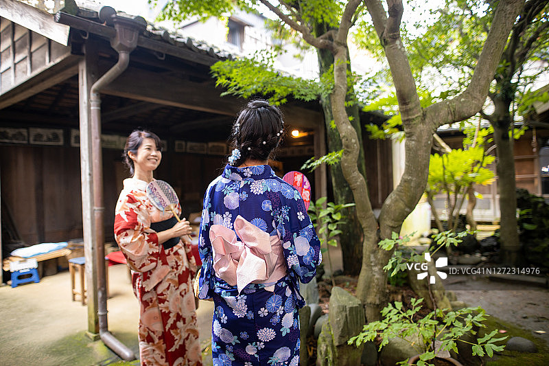 母亲和女儿在浴田在古老的日本花园交谈图片素材