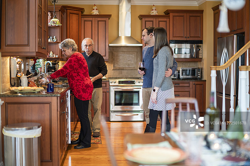 两代人的家庭，年轻夫妇和老夫妇，一起在厨房里工作图片素材