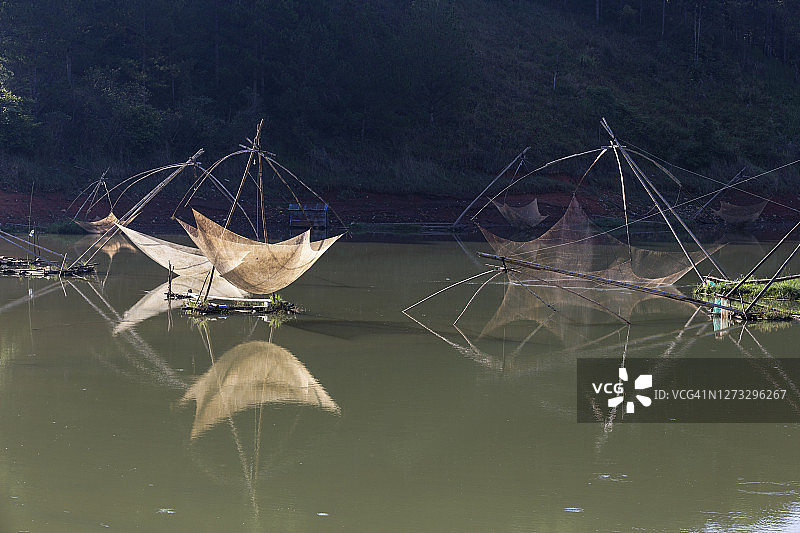 孤独的渔民在湖边的渔场收获，神奇的渔网和独特的日出风景如童话般图片素材