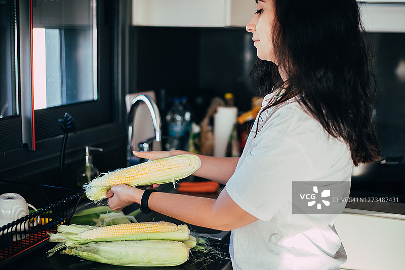 在厨房做饭前剥玉米的妇女图片素材