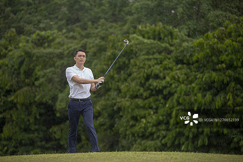 亚洲华人成熟男子高尔夫球手在高尔夫球场打高尔夫开球挥杆图片素材