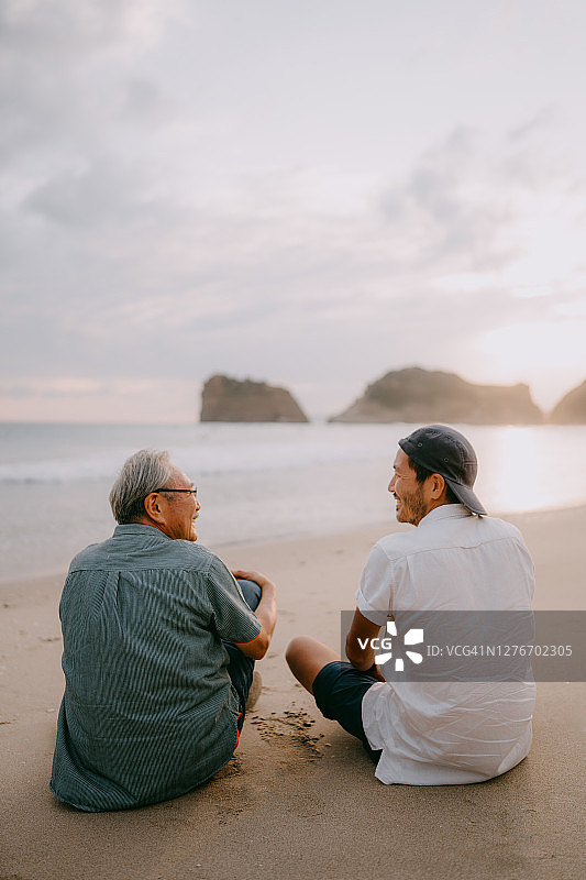 年长的父亲和儿子在日落时分的海滩上度过了美好的时光图片素材