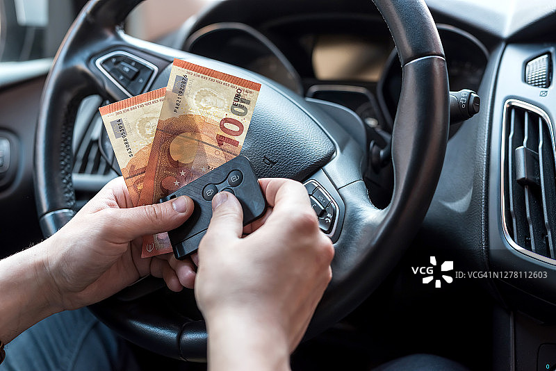 一名男子在车里数欧元，以支付停车费或货物费用图片素材