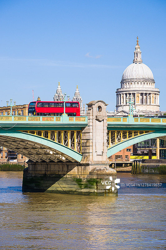 伦敦红色巴士穿过圣保罗大教堂下的泰晤士河图片素材