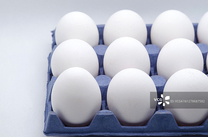 白色的鸡蛋装在蓝色的纸盒里，白色的背景图片素材