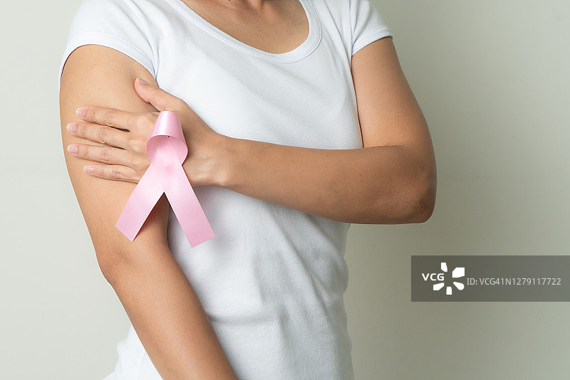 粉红色的徽章丝带在妇女的手触摸胸部，以支持乳腺癌的事业。认识乳癌概念图片素材