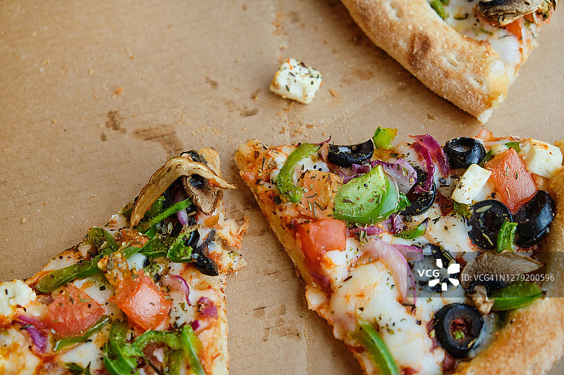 在咖啡馆或披萨店的木桌上，用纸板箱或外带包装的意大利蔬菜披萨，配奶酪和蘑菇。素食。快餐。图片素材