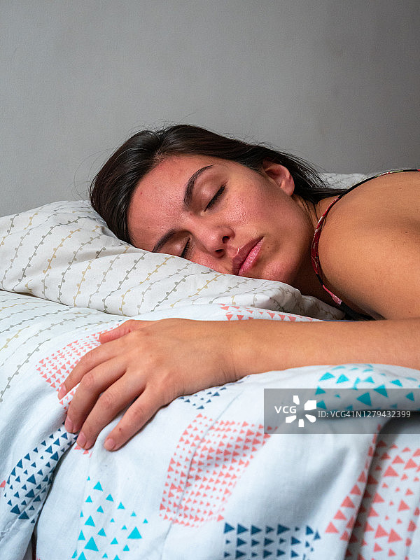 年轻的棕色头发西班牙女性睡在她的床上图片素材