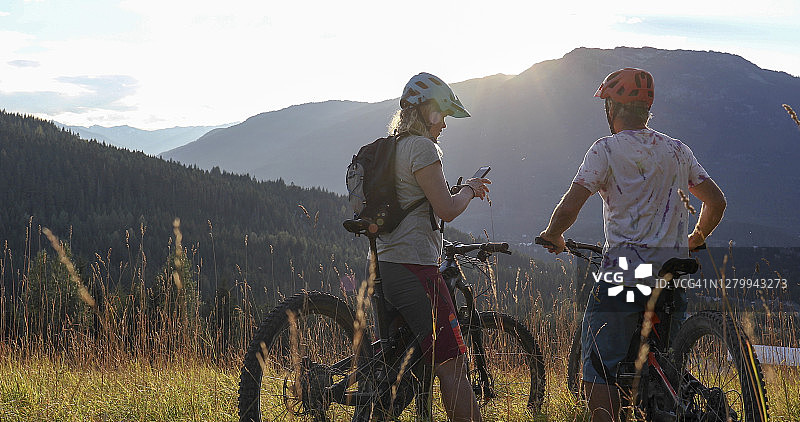 骑电动自行车的情侣在高山草甸中放松图片素材