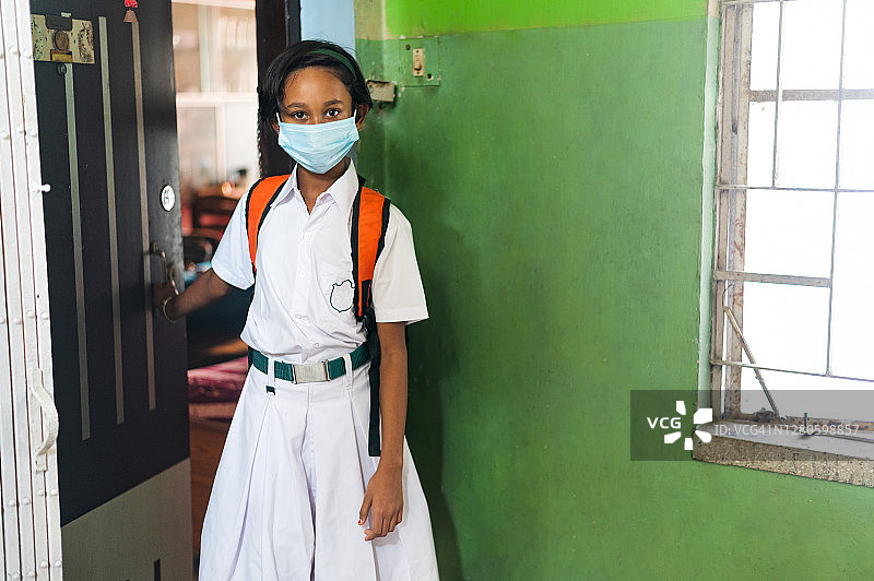 印度女学生戴着口罩上学以预防COVID-19。图片素材