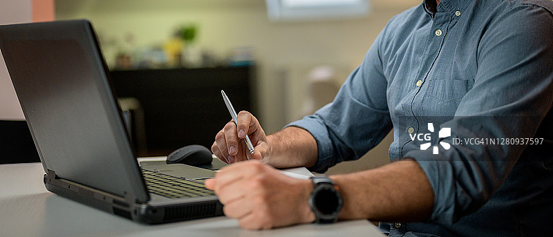 一名男子用笔记本电脑在家学习的镜头。图片素材