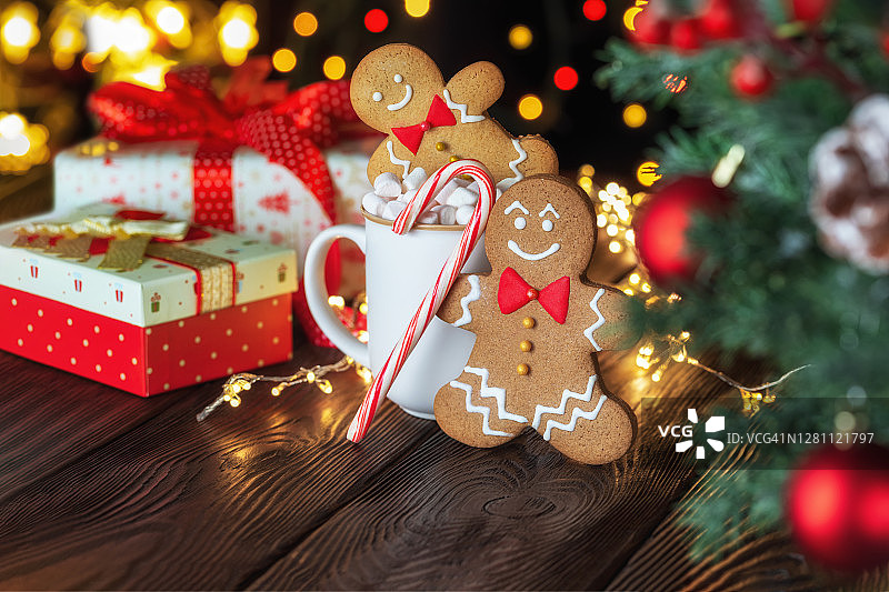 圣诞节自制的姜饼人，糖果手杖和杯子与棉花糖在质朴的木桌上。图片素材