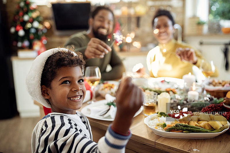 快乐的黑人男孩在和他的家人一起庆祝圣诞节的时候和烟火玩得很开心。图片素材