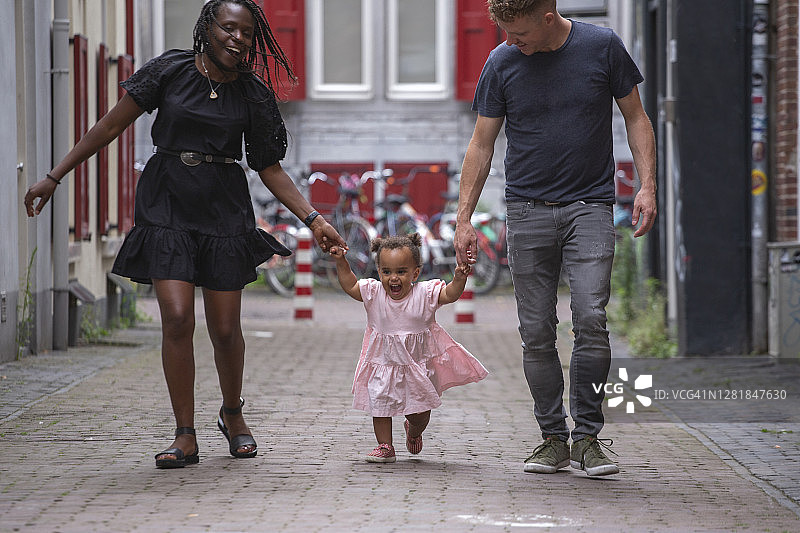 一个混血家庭带着他们的小女儿穿过城市图片素材