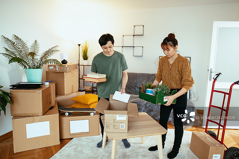 一对千禧一代的日本夫妇搬着盆栽搬进了新的出租公寓图片素材