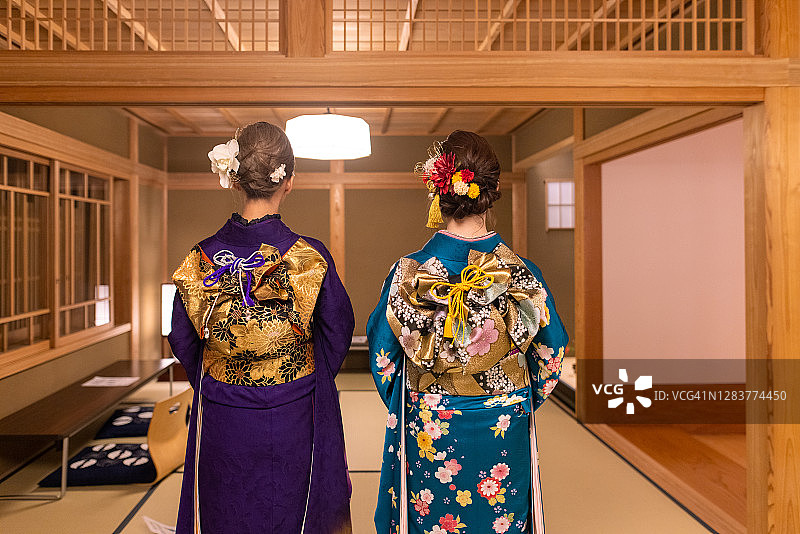 身穿Furisode和服的年轻女子站在Ryokan酒店榻榻米房间的后视图图片素材