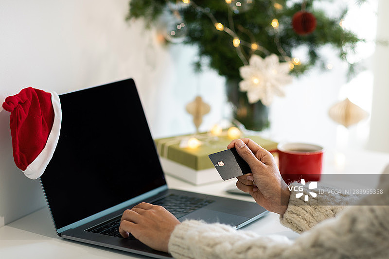 用信用卡在网上买圣诞礼物的女人。图片素材