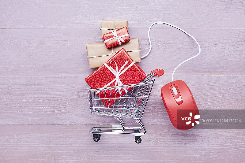 静物小购物车，礼物和红色电脑鼠标放在紫色木桌上，网上购物图片素材
