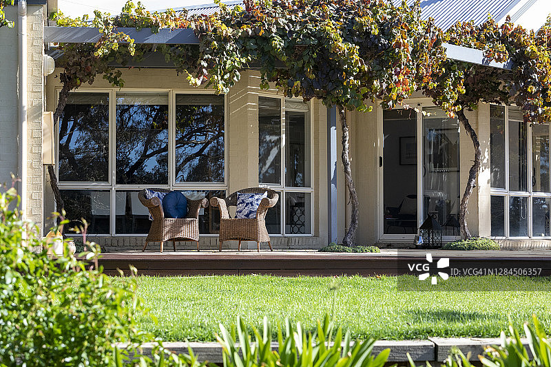 视野穿过花园和草坪到房子前面的柳条椅子图片素材