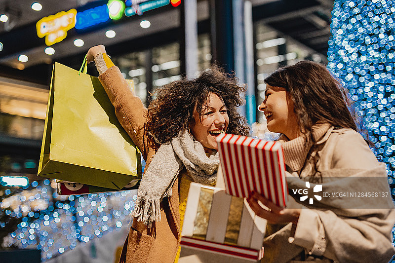 两个兴奋的女性朋友在假日购物图片素材