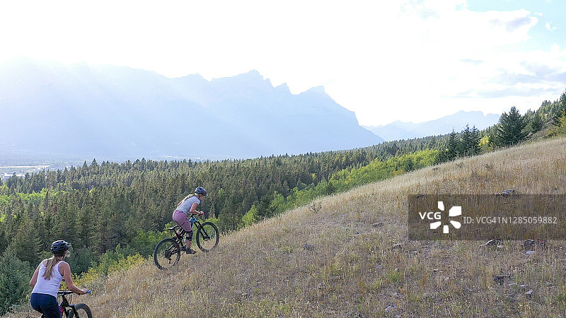 山地自行车手在山谷和山脉上方的旷野上骑行图片素材