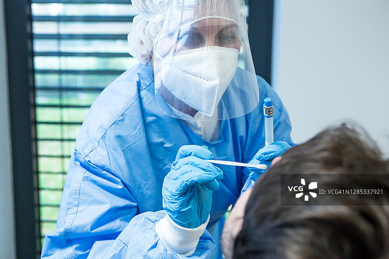 流行病-身着防护服的医务人员从病人的鼻子中提取样本。图片素材