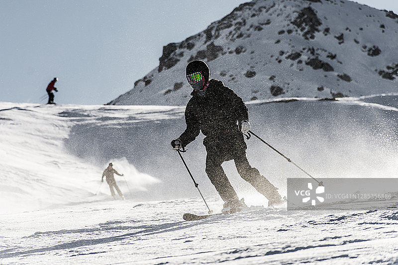 三个滑雪者在西班牙阿拉贡福米加尔的一个斜坡上滑雪。滑雪者参加在雪地上滑行的比赛。水平的照片图片素材