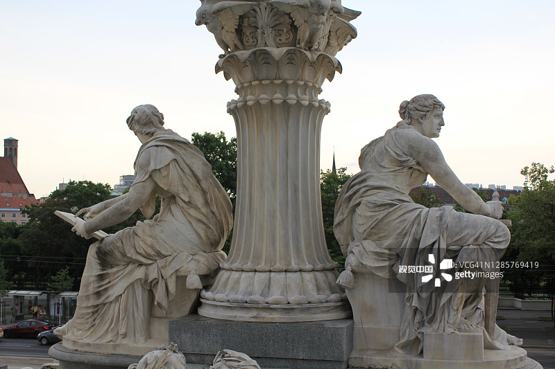 两个女人坐在议会大厦前的雕塑，维也纳，奥地利图片素材