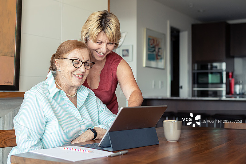 家庭护工帮助老年患者使用平板电脑与家人视频聊天图片素材