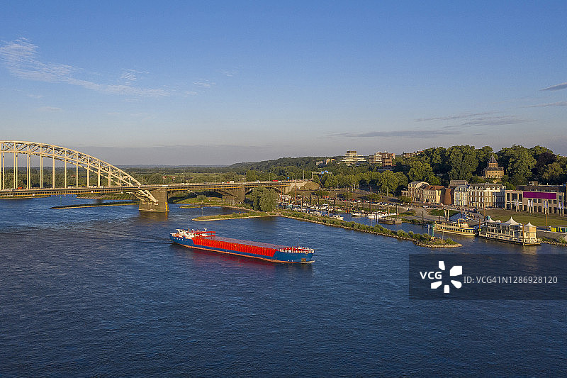 荷兰，格尔德兰，奈梅亨，集装箱船通过瓦尔河大桥的鸟瞰图图片素材