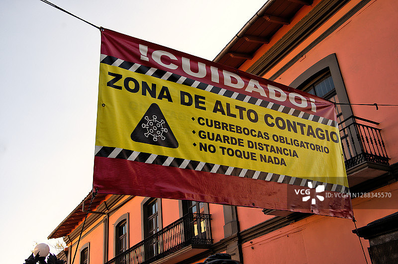 西班牙语covid-19健康和安全标志横幅悬挂在一个户外步行购物中心图片素材