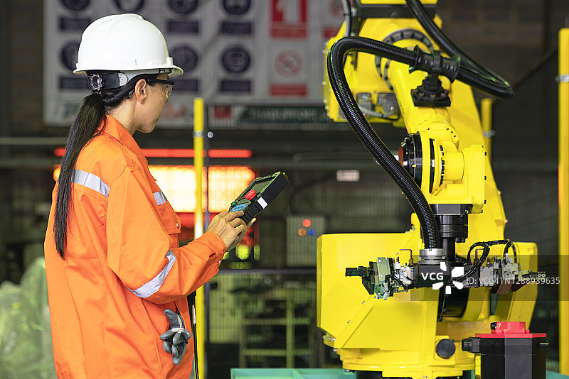 工程师在自动化工厂进行教学后检查了机器人的方向。图片素材