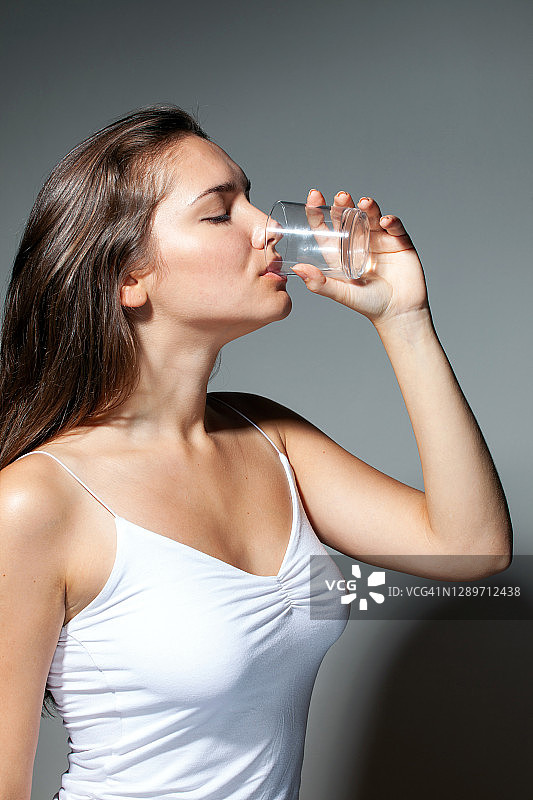 用玻璃杯喝水的女人图片素材