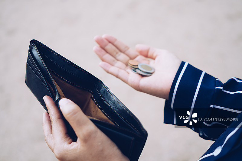 女人手里拿着一个空钱包和硬币意味着钱有问题或破产失业，信用卡破产后发薪日失业，债务概念。图片素材