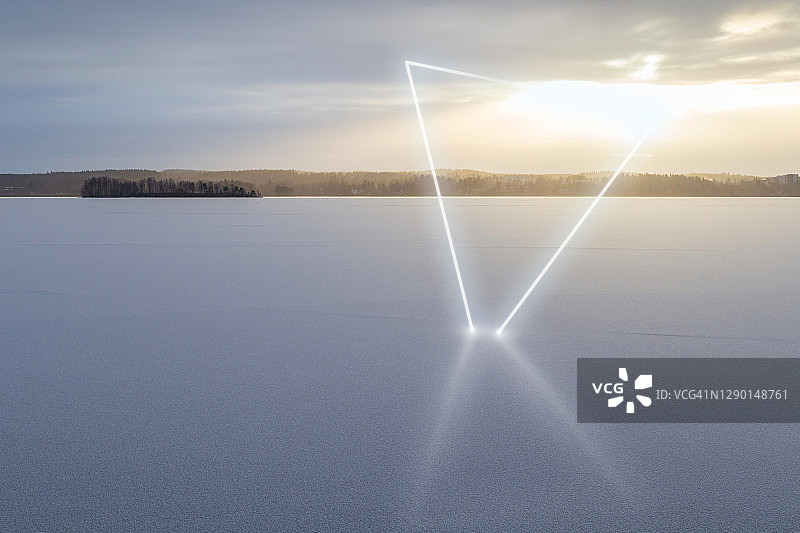 在芬兰的冬天，阳光明媚的日子里，冰雪覆盖的湖面上，充满未来感的白色发光霓虹灯三角形。图片素材