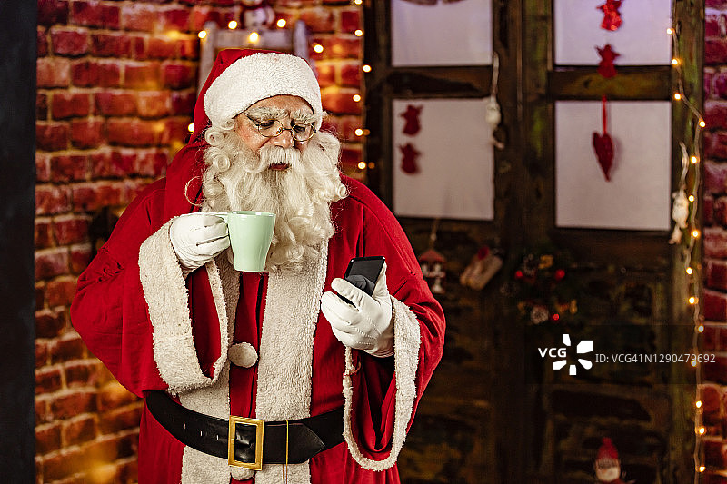 圣诞老人使用智能手机在café图片素材