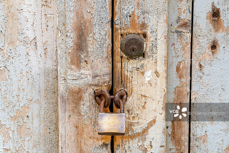 一扇旧木门，有一个破旧的挂锁。这张照片非常适合封锁和关闭。图片素材